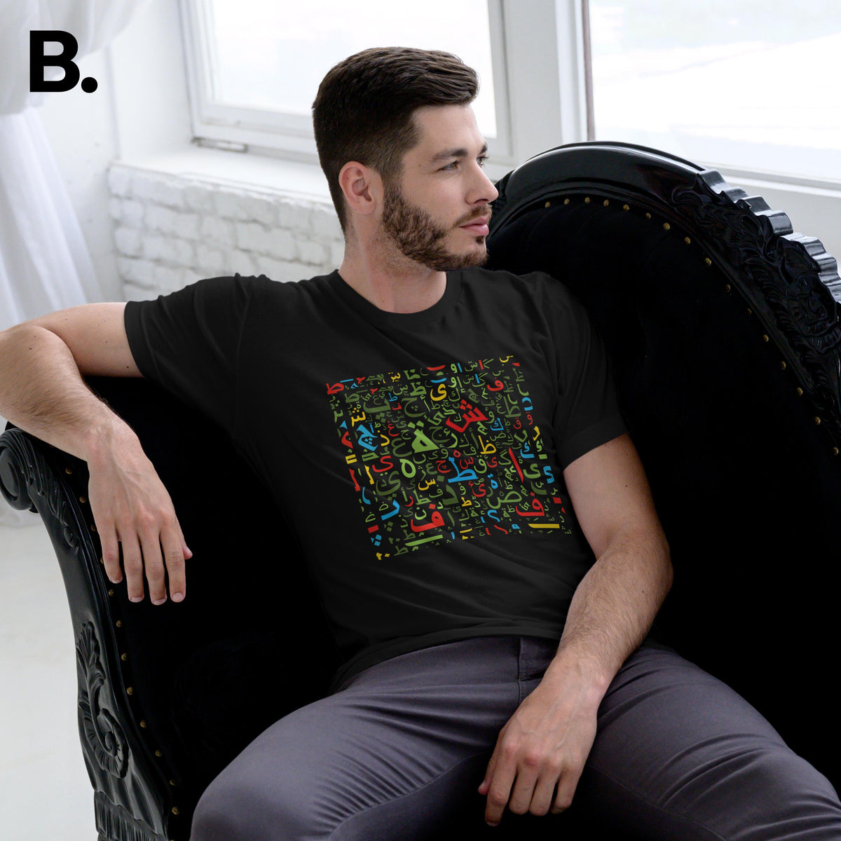 Seated model wearing the black Calli tee with multicoloured calligraphy lettering