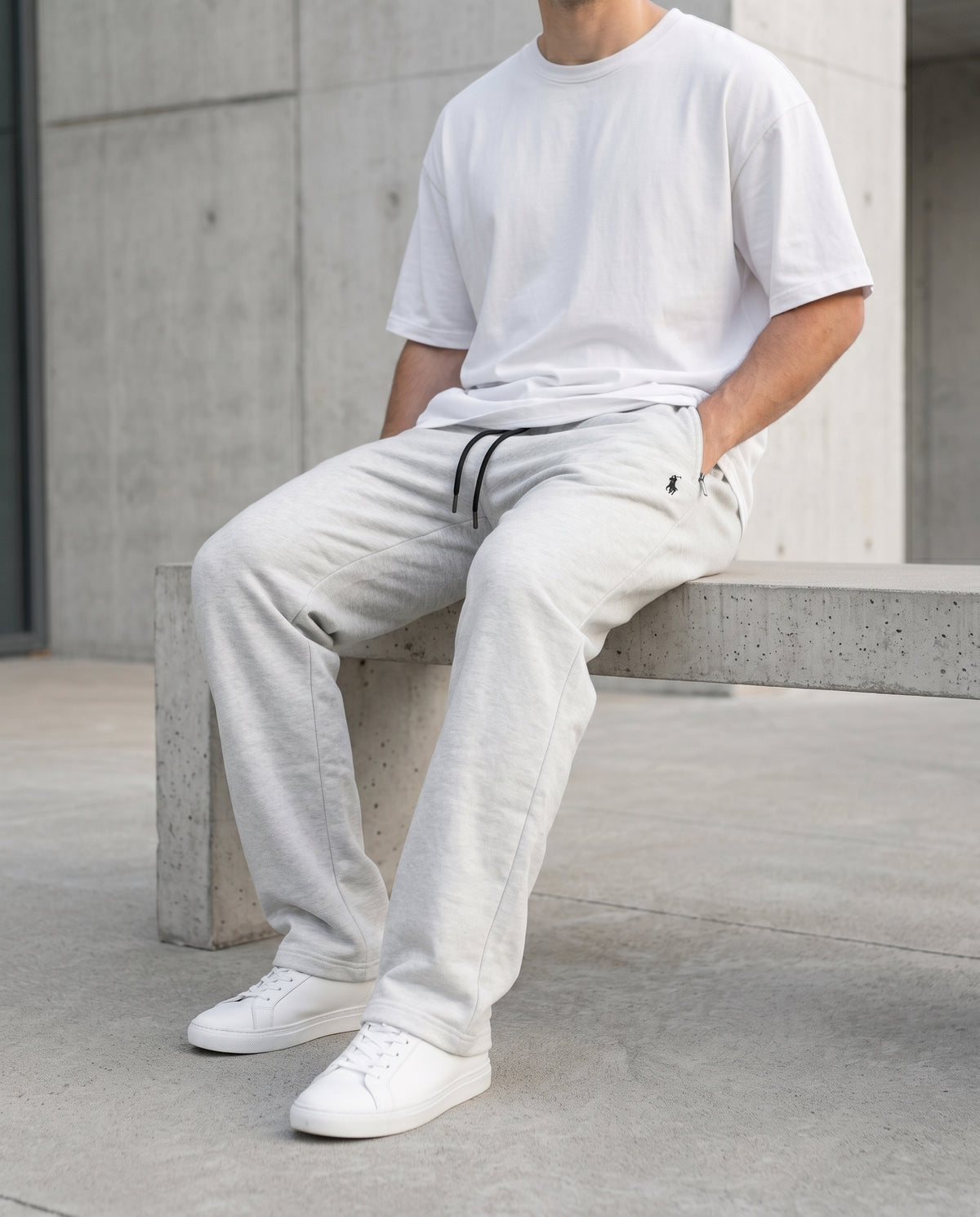 Model seated wearing Grey cotton terry trousers with a drawstring waistband